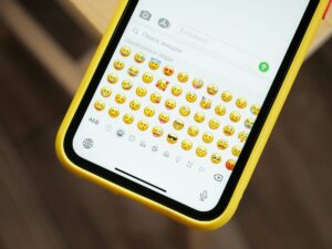 iPhone jaune affichant de nombreux emojis sur le clavier